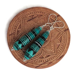 May include: Teal and black geometric patterned dangle earrings with silver hooks.