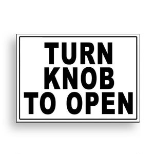 May include: Black and white sign with the text "TURN KNOB TO OPEN" in bold, uppercase letters.