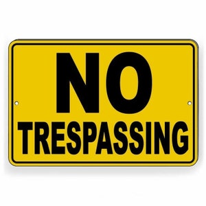 May include: A yellow metal sign with black text that reads "NO TRESPASSING".