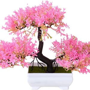 May include: A pink artificial bonsai tree in a white ceramic pot. The tree has a thick, dark brown trunk and many branches with small pink leaves.