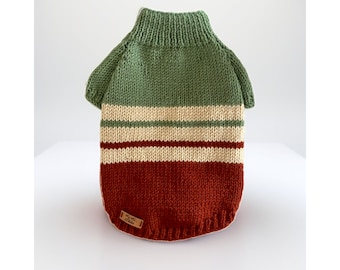 May include: A green, cream and rust coloured knitted sweater for a pet. The sweater has a turtleneck and a striped pattern.