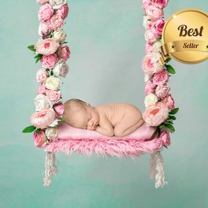 May include: A newborn baby sleeping on a pink swing decorated with pink and white flowers. The swing is suspended from a white ceiling. The image has a "Best Seller" badge.