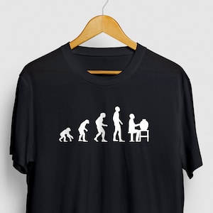 May include: Black t-shirt with a white graphic depicting the evolution of man, culminating in a person sitting at a computer. The design shows a progression from ape to human, with the final stage at a desk.