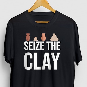 May include: Black t-shirt with a white graphic of five clay pots in different shades of brown and the text "SEIZE THE CLAY".