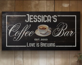May include: Black wooden sign with white text that reads "Jessica's Coffee Bar Est. 2023 Love is Brewing". A white coffee cup with a brown coffee drink is pictured on the sign.