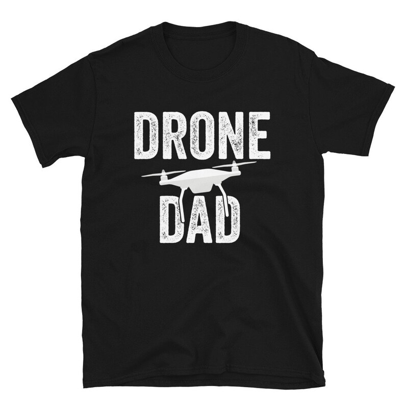 May include: Black t-shirt with white text that reads "Drone Dad" and a white silhouette of a drone.