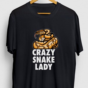 Może przedstawiać: Czarny T-shirt z grafiką węża i tekstem "Crazy Snake Lady".