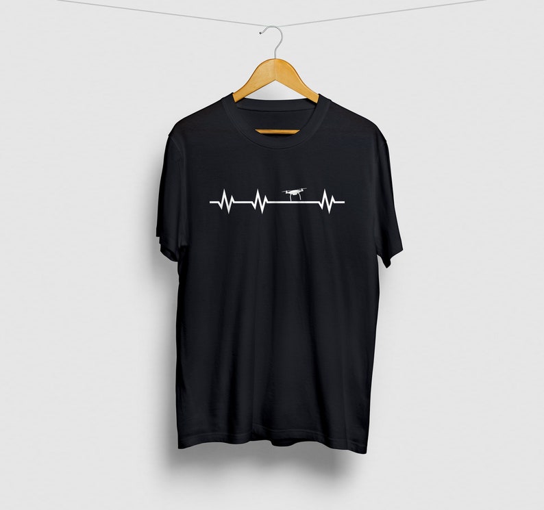 May include: Black t-shirt with a white graphic of a drone flying over a heartbeat line.