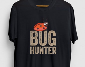 Può includere: Maglietta nera con una coccinella dei cartoni animati e il testo "BUG HUNTER" in un font usurato.