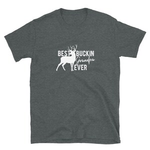 K&ouml;nnte beinhalten: Ein dunkelgraues T-Shirt mit einer wei&szlig;en Silhouette eines Hirsches und dem Text "Best Buckin' Grandpa Ever".