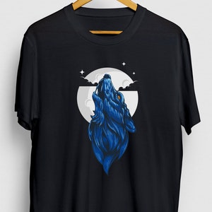 May include: A black t-shirt with a blue wolf howling at the moon graphic. The moon is white with a blue sky and clouds. There are stars in the sky.