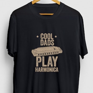 May include: Black t-shirt with the text "Cool Dads Play Harmonica" in brown text with a graphic of a harmonica.