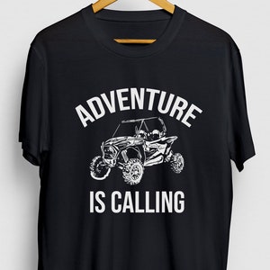 May include: Black t-shirt with white text that reads "Adventure is Calling" and a graphic of a white off-road vehicle.