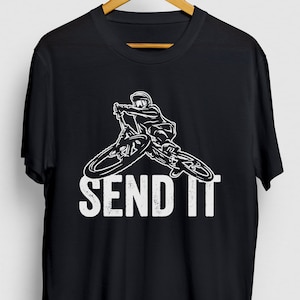 Puede incluir: Camiseta negra con un gráfico blanco de una persona montando una bicicleta de montaña y el texto "SEND IT".
