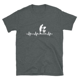 May include: A dark heather gray t-shirt with a white graphic of a person grilling on a barbecue grill with a heartbeat line above it.