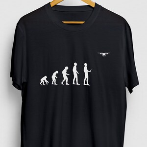 May include: Black t-shirt with a white graphic of the evolution of man, ending with a man holding a remote control and a drone flying above. The text reads "Drone Evolution".
