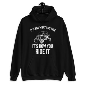 Op de afbeelding: Zwarte hoodie met een witte afbeelding van een terreinwagen en de tekst "Het gaat er niet om wat je rijdt, maar hoe je rijdt."