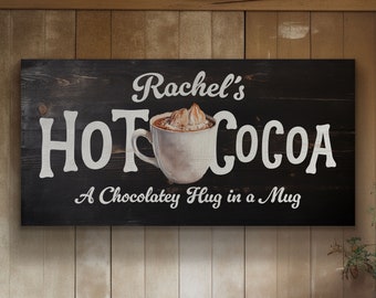 Pode incluir: Placa de madeira preta com texto branco que diz "Rachel's Hot Cocoa A Chocolatey Hug in a Mug". A placa apresenta uma caneca branca com um líquido castanho e chantilly branco no topo.