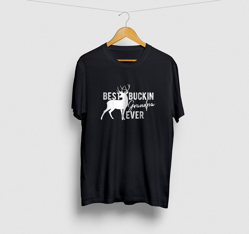K&ouml;nnte beinhalten: Schwarzes T-Shirt mit einer wei&szlig;en Silhouette eines Hirsches und dem Text "Best Buckin' Grandpa Ever".