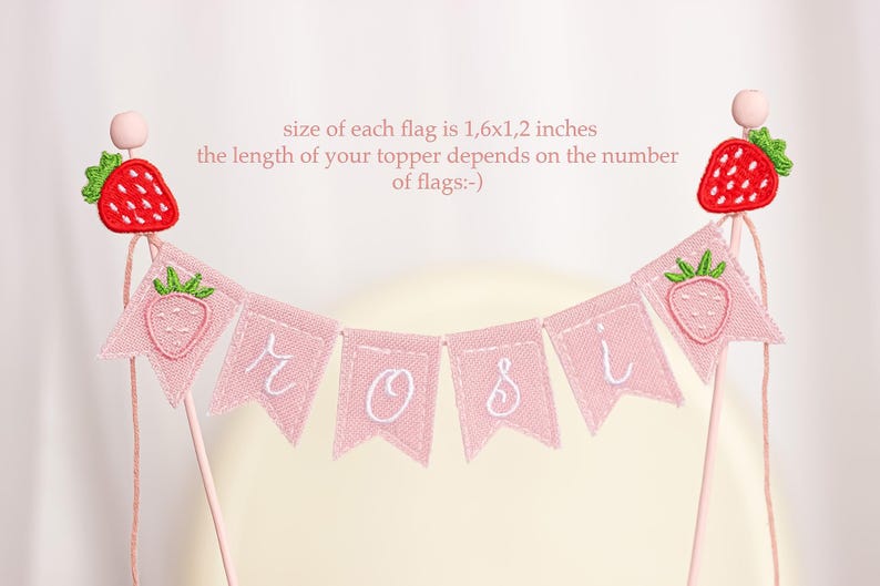 Embroidered name cake topper on pink cotton flags with strawberries on each end. Personalized topper for berry first birthday celebration.