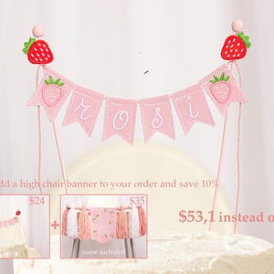 Embroidered name cake topper on pink cotton flags with strawberries on each end. Personalized topper for berry first birthday celebration.