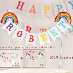May include: A cake topper with a rainbow and the name "ROBERT" spelled out on a banner. The topper is on a white cake. The image also shows two other cake toppers, one with a rainbow and the text "HAPPY BIRTHDAY ZOE" and another with a rainbow and the text "HAPPY ROBERT".