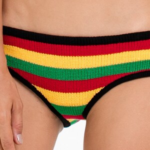 Puede incluir: Ropa interior a rayas con rayas negras, rojas, amarillas y verdes. La ropa interior tiene una cintura negra.