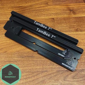 May include: Two black plastic TamBee 7" printer bed leveling tools with the text "TamBee 7" printed on them. The tools are on a wooden surface.