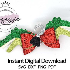 Puede incluir: Un lazo de brillo rojo, verde y blanco con un dije de gancho negro. El lazo tiene forma de cabeza de cocodrilo. El texto "Descarga digital instantánea SVG DXF PNG PDF" está debajo del lazo.