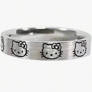 May include: A silver ring with a brushed finish and multiple engraved Hello Kitty faces.
