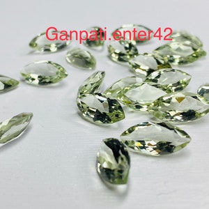May include: A collection of light green marquise cut gemstones. The stones are faceted and have a translucent appearance.