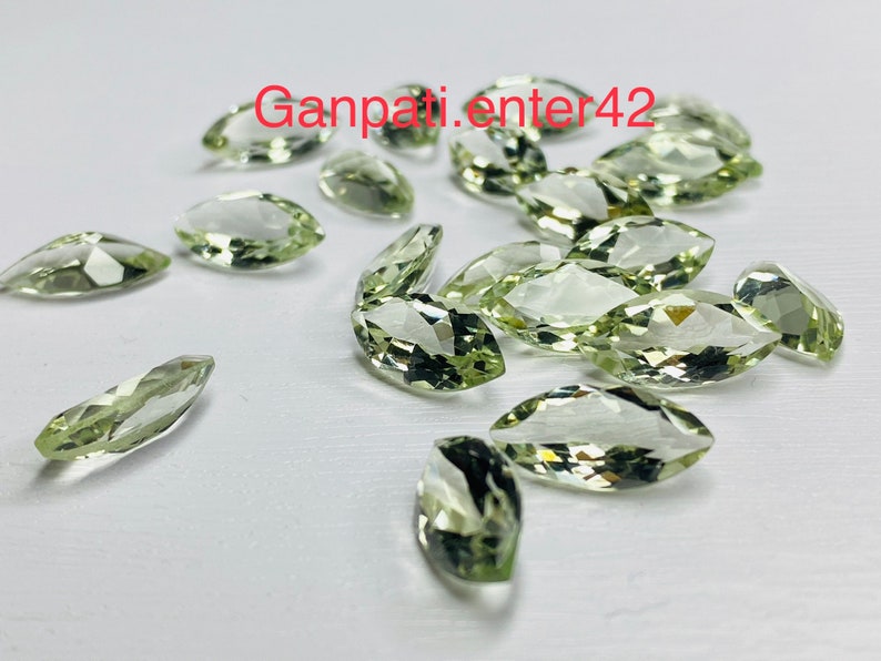 May include: A collection of light green marquise cut gemstones. The stones are faceted and have a translucent appearance.
