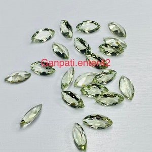 May include: A collection of 18 marquise-shaped green gemstones. The stones are faceted and have a light green color.