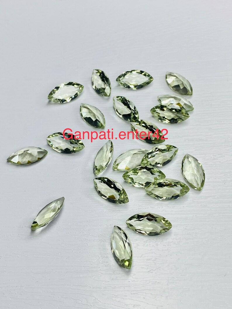 May include: A collection of 18 marquise-shaped green gemstones. The stones are faceted and have a light green color.