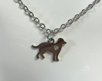 Puede incluir: Un collar de plata con un dije con la silueta de un perro. El perro tiene un corazón cortado en su pecho.