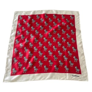May include: A square scarf featuring a vibrant red center panel decorated with a repeating pattern of small black and white sheep illustrations. The scarf is framed by a wide, solid off-white border, with the brand name Pendleton printed in black.