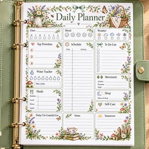 Peut inclure: Une page de planification quotidienne insérée dans un classeur vert sauge. La page présente des illustrations florales, un papillon et des sections pour la date, l'humeur, la météo, les priorités, l'emploi du temps, les tâches et les notes.
