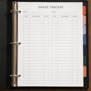 Puede incluir: Un archivador negro abierto en una página blanca con la etiqueta "GRADE TRACKER". La página está dividida en columnas para "DATE", "ASSIGNMENT" y "GRADE". Las pestañas en tonos naranja, rosa, morado, azul y verde son visibles a la derecha. El archivador está sobre una superficie de madera.
