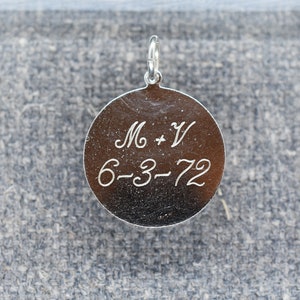 May include: Silver round charm with the inscription "M + V 6-3-72" engraved on the front.