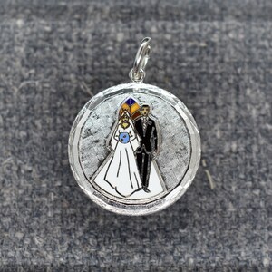 May include: Silver charm with a white enamel bride and groom in a wedding ceremony. The charm has a textured silver background.