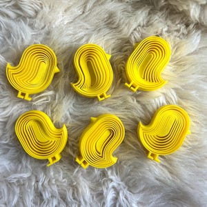 May include: A set of three ceramic mugs with a speckled, matte finish. The mugs are in shades of cream, light brown, and dark brown. Each mug has a simple, minimalist design, perfect for coffee or tea.