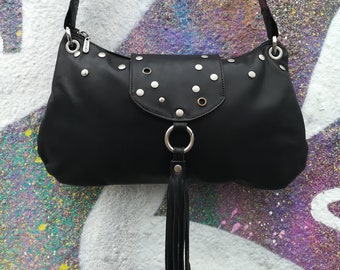 May include: A black leather shoulder bag with silver studs and a black tassel. The bag has a flap closure and a silver ring on the front.