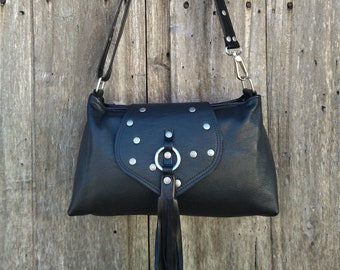 May include: A black leather shoulder bag with silver studs and a fringe detail. The bag has a flap closure with a silver ring and a strap.