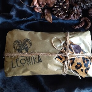May include: A brown paper parcel tied with twine and a leopard print gift tag. The parcel is labelled "LEONIKA" and features a black and white illustration of a goat's head.