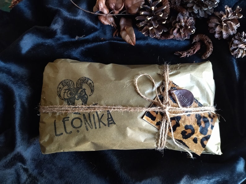 May include: A brown paper parcel tied with twine and a leopard print gift tag. The parcel is labelled "LEONIKA" and features a black and white illustration of a goat's head.
