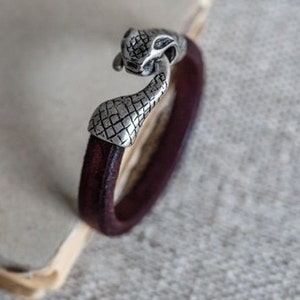 May include: A brown leather bracelet with a silver snake head clasp.
