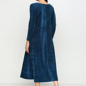 May include: A long-sleeved, teal blue velvet dress with a round neckline. The dress has a slightly flared skirt and is shown on a model wearing white sneakers.