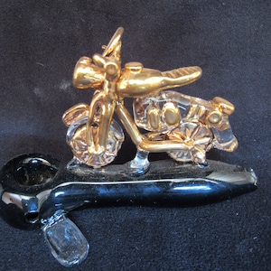 Hand blown glass motorcycle on a pipe.
