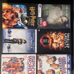May include: A collection of six DVD cases featuring various movies, including "Harry Potter and the Sorcerer's Stone", "Speak", "Thirteen Ghosts", "Edward Scissorhands", "Spice World", and "Major League: Back to the Minors".