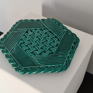 Puede incluir: Un posavasos hexagonal de cerámica verde con un diseño tejido y un borde de cuerda.